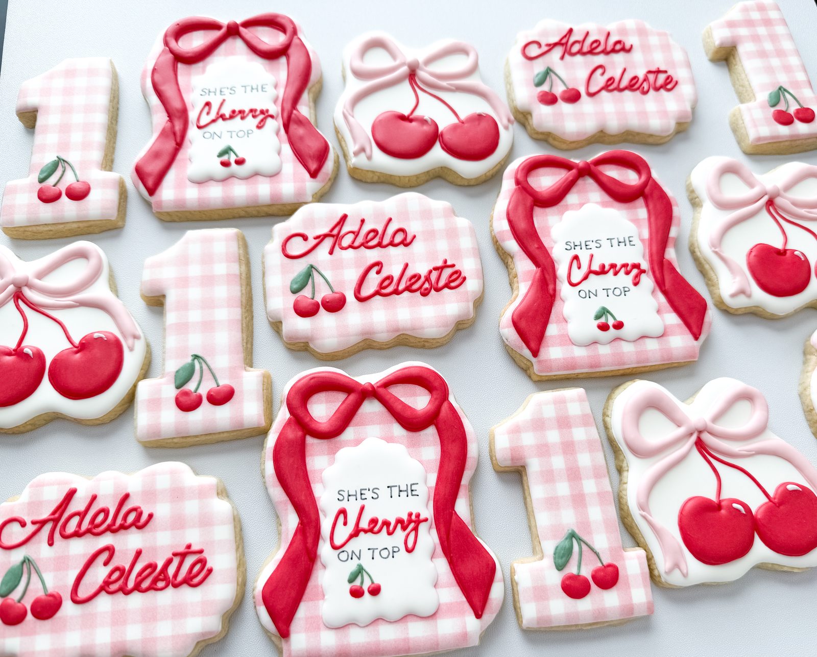 She's the Cherry on Top first birthday cookies with pink gingham, cherries, and bows