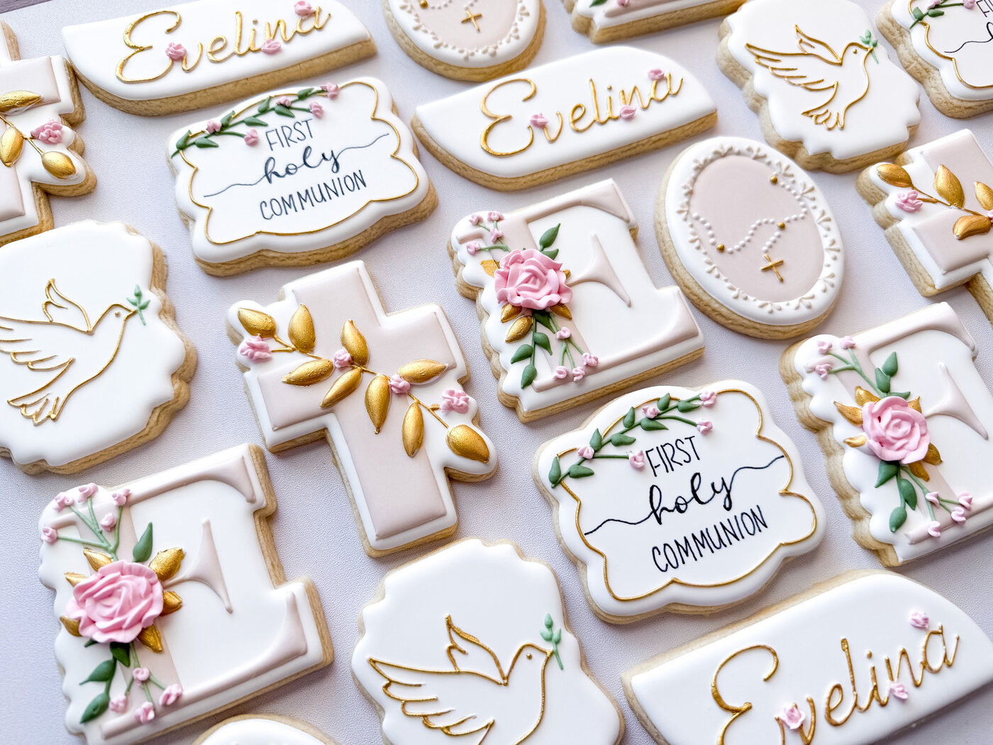 First Holy Communion cookies with gold crosses, doves, rosaries, pink roses, and custom name