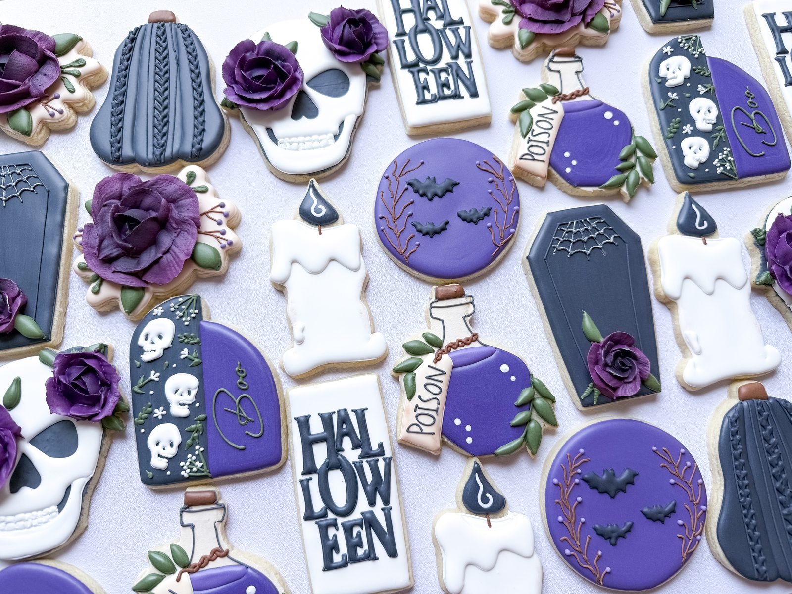 Floral gothic Halloween cookies with skulls, purple roses, coffins, candles, and poison bottles