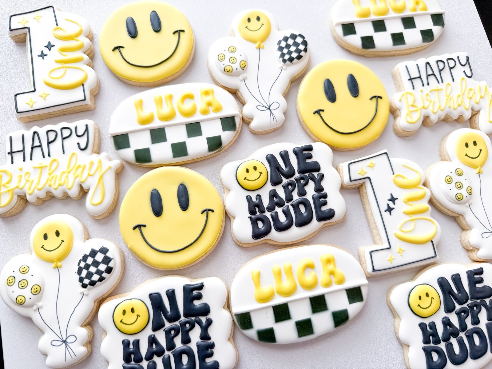One Happy Dude first birthday cookies with smiley faces, checkered accents, and balloons