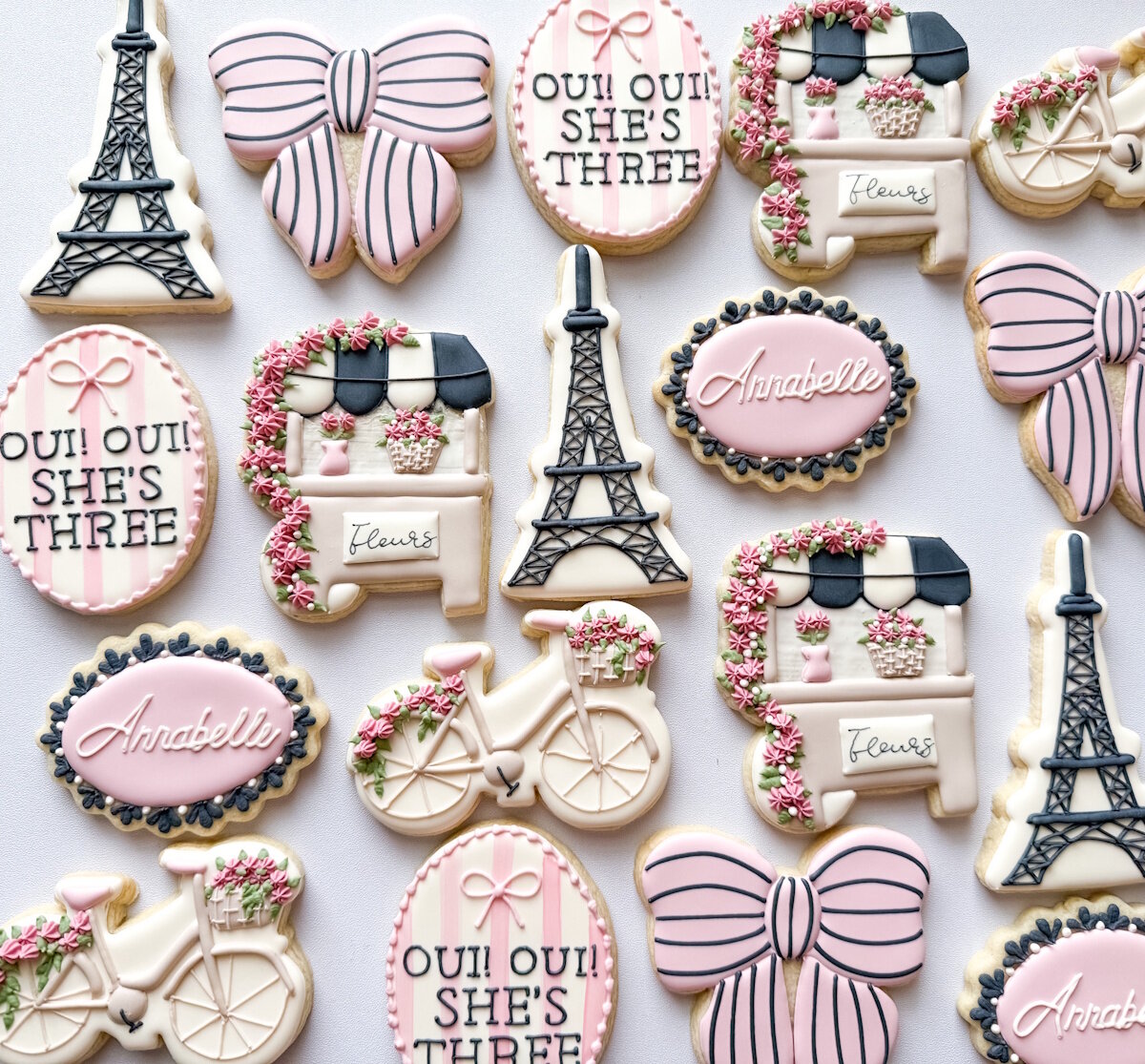 Paris themed birthday cookies with Eiffel Towers, flower carts, bicycles, and striped bows