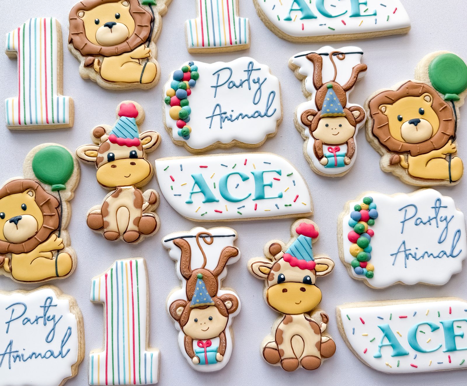 Party Animal safari first birthday cookies with lions, giraffes, monkeys, and custom name plaques