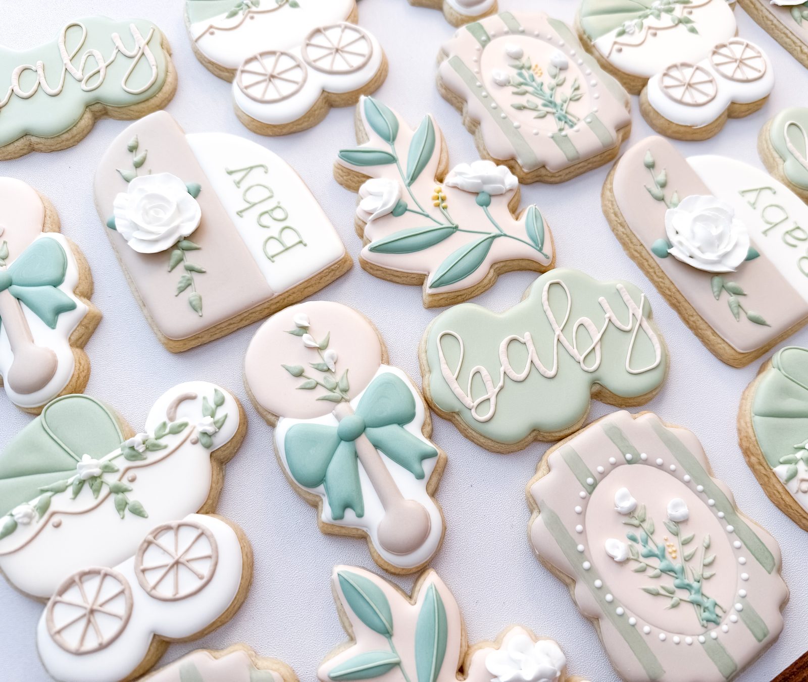 Sage and cream floral baby shower cookies with vintage prams, rattles, and piped roses