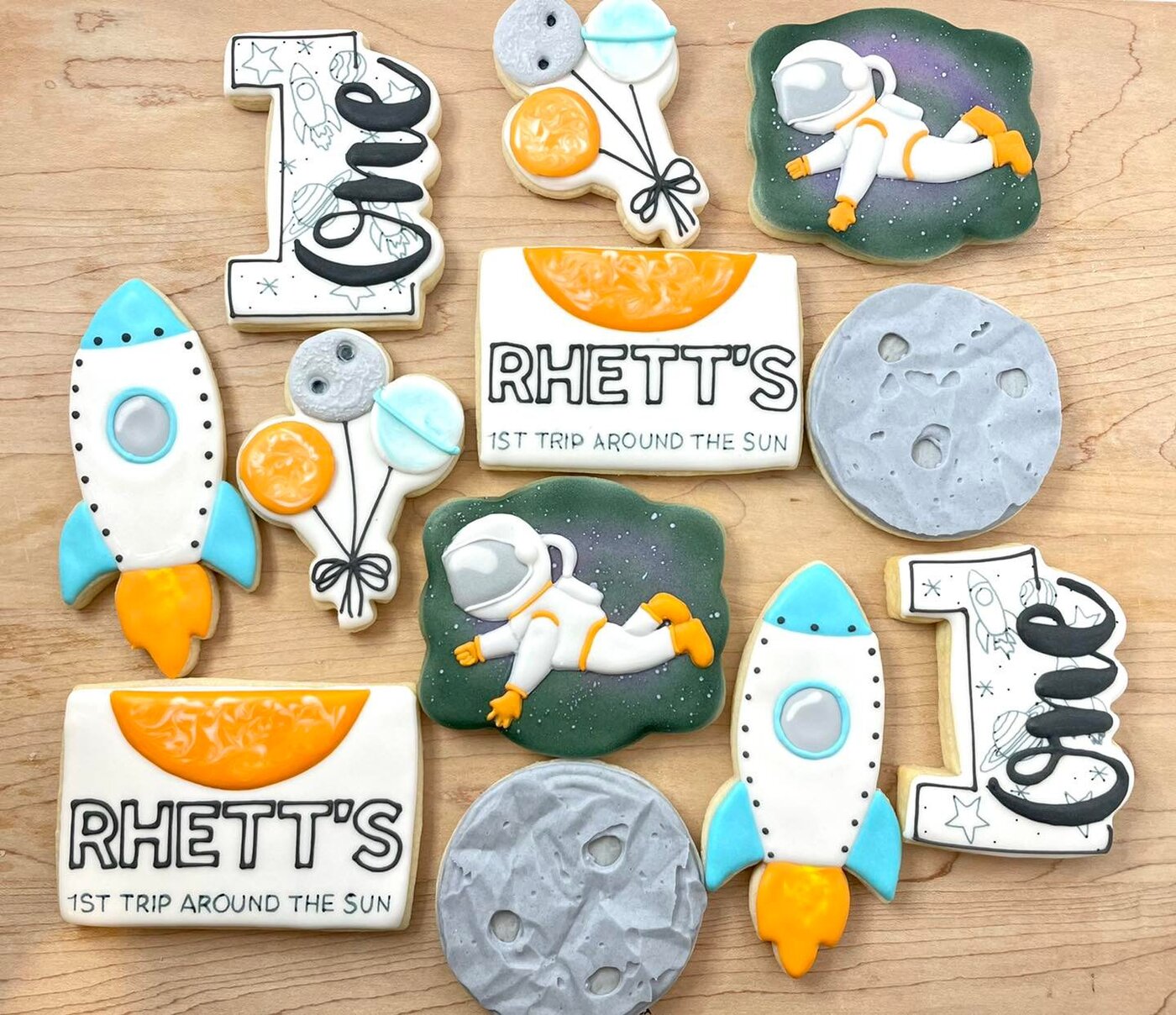 Space themed first birthday cookies with rockets, astronauts, moons, and a custom name plaque