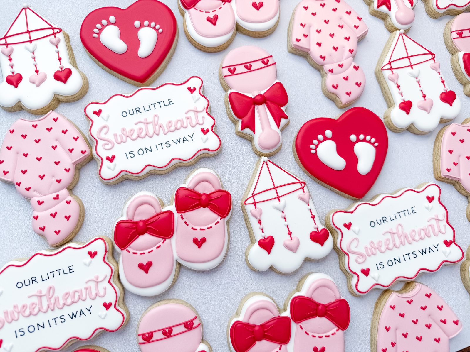 Our Little Sweetheart Valentine baby shower cookies with baby feet hearts, rattles, and booties