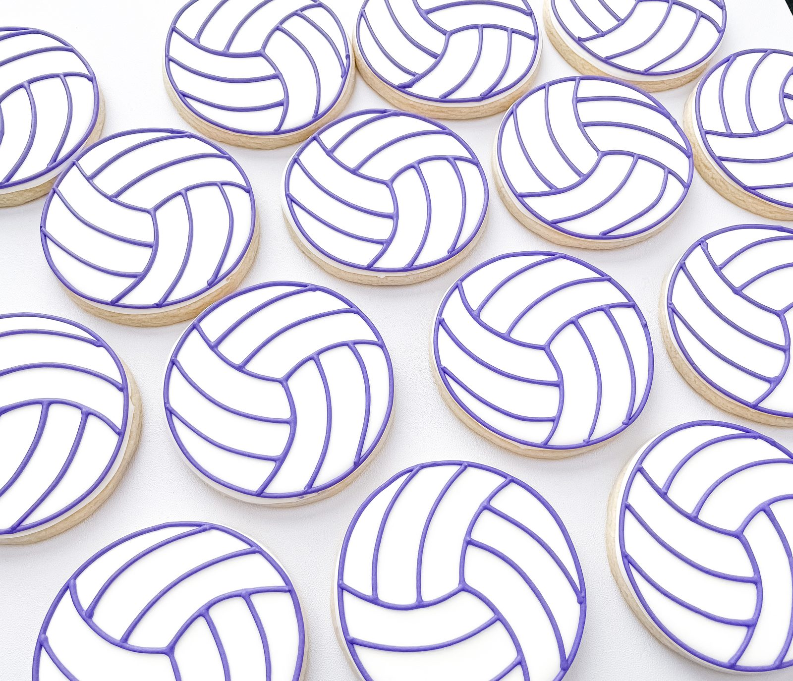 Volleyball cookies with purple piped detail on round white icing