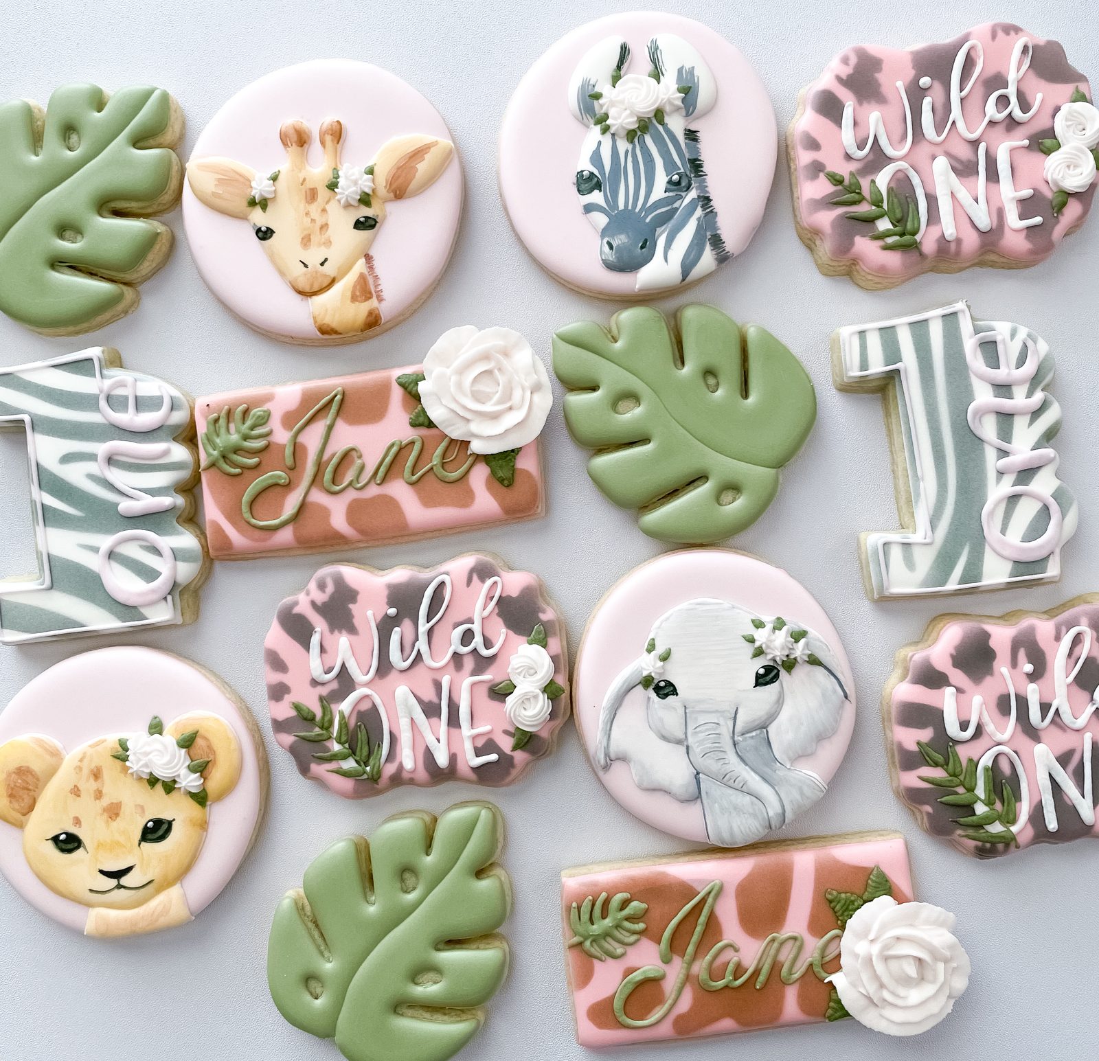 Wild One safari birthday cookies with hand-painted giraffe, zebra, elephant, and lion cub
