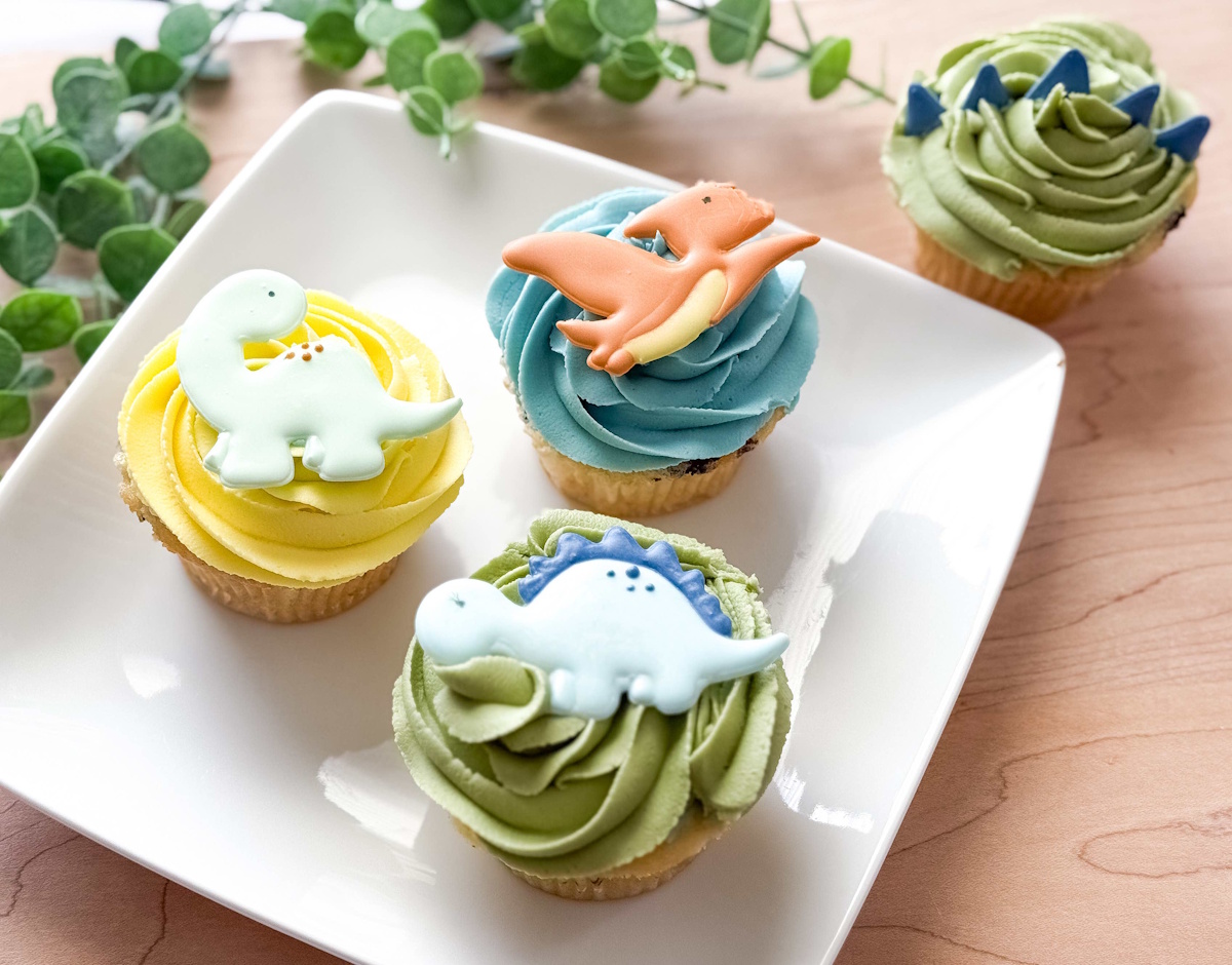 Dinosaur birthday cupcakes with royal icing dino toppers in green, blue, and yellow
