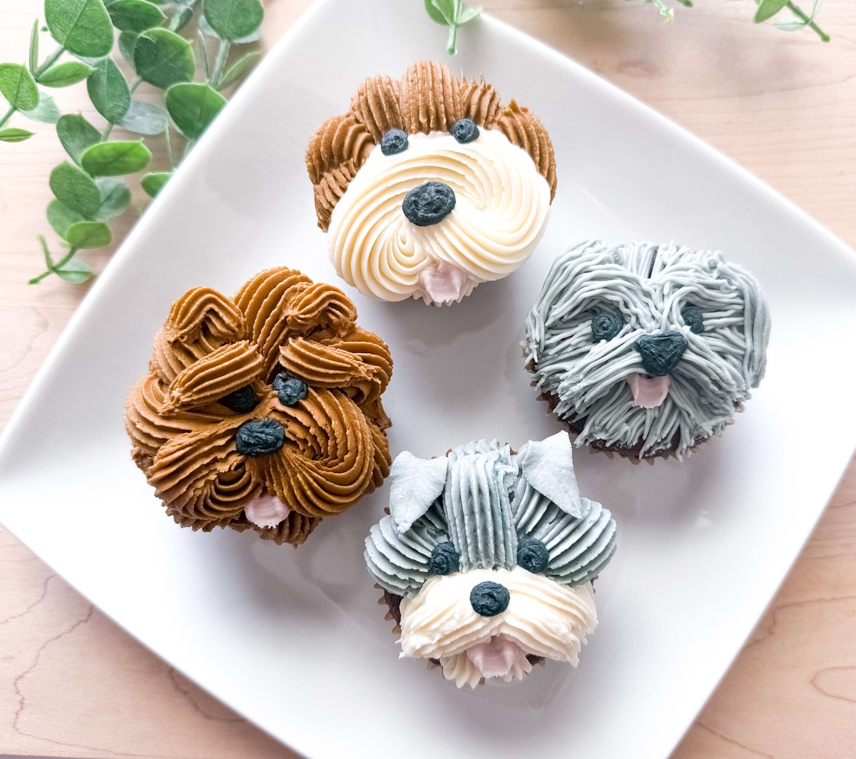 Puppy cupcakes piped as four different dog breeds in buttercream