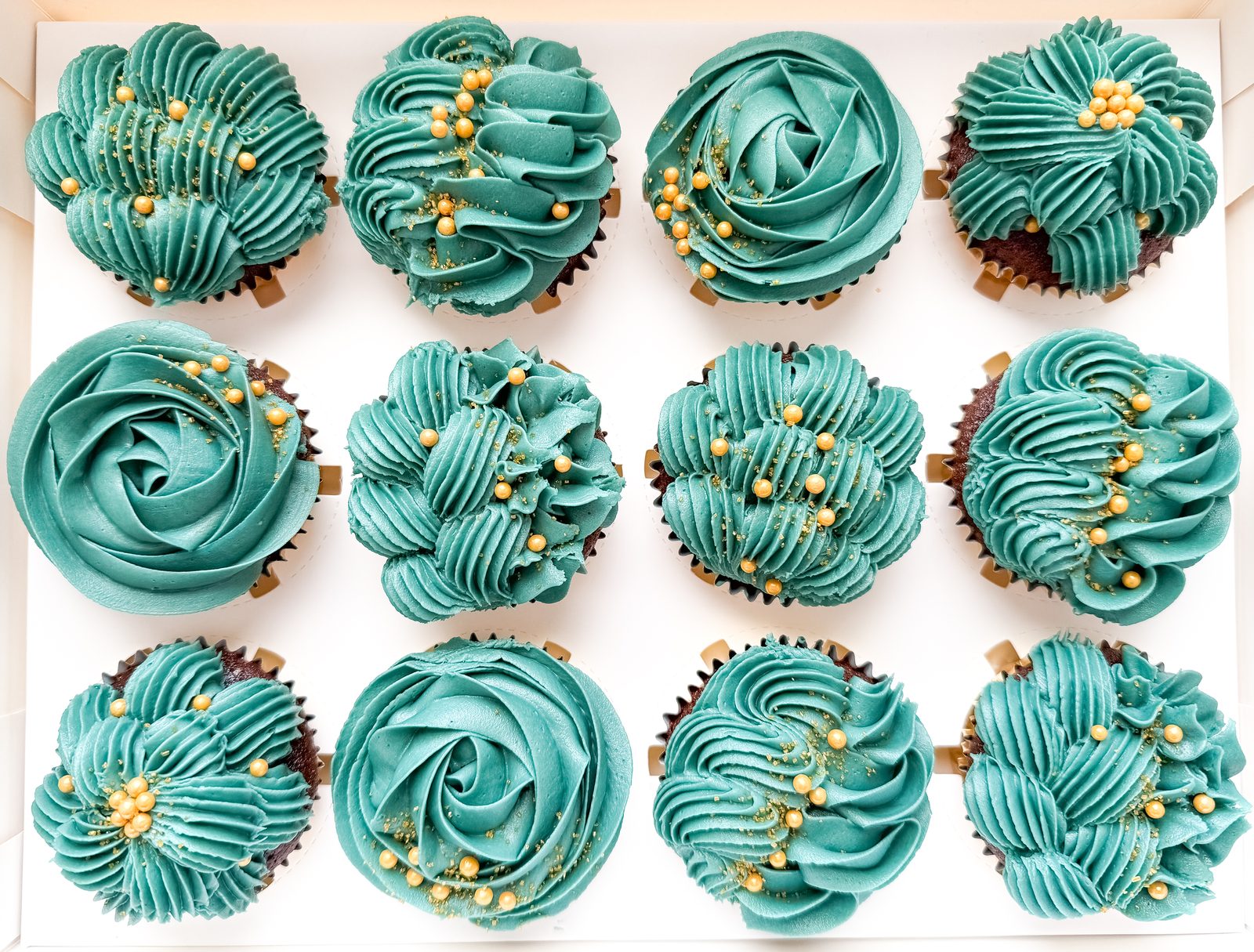 Teal buttercream cupcakes with rosettes, shell piping, and gold sugar pearls